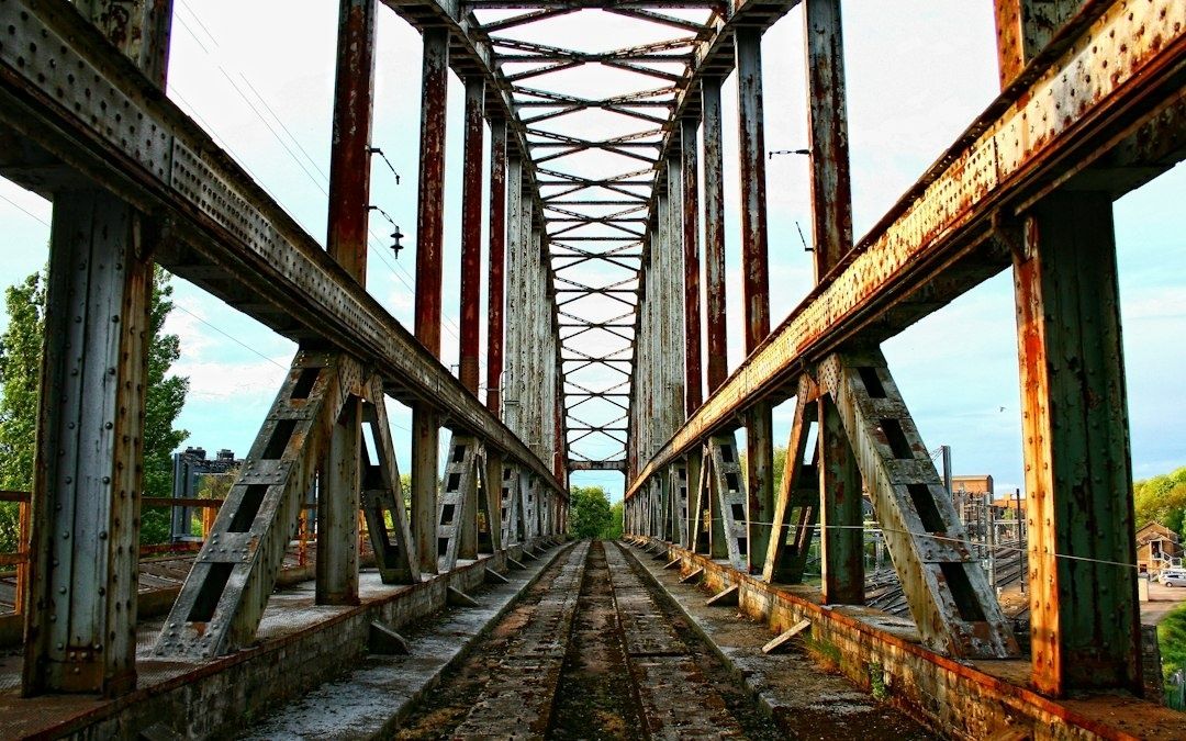 Oude, roestige spoorbrug met rails en stalen vakwerkconstructie